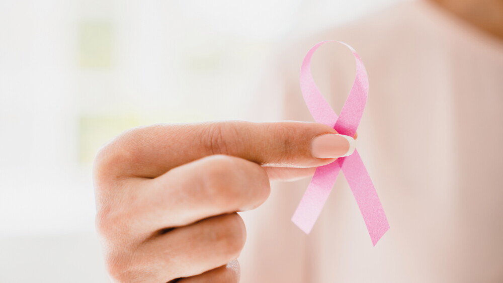 Cropped close-up shot of caucasian woman in pink t-shirt holding pink ribbon for supporting breast cancer movement. World cancer day concept
