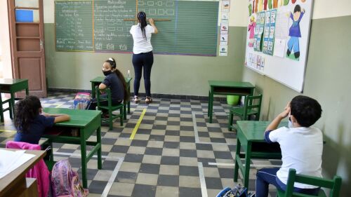 En aula. Una docente escribe en el pizarrón ante la atenta mirada de sus alumnos en la sala.