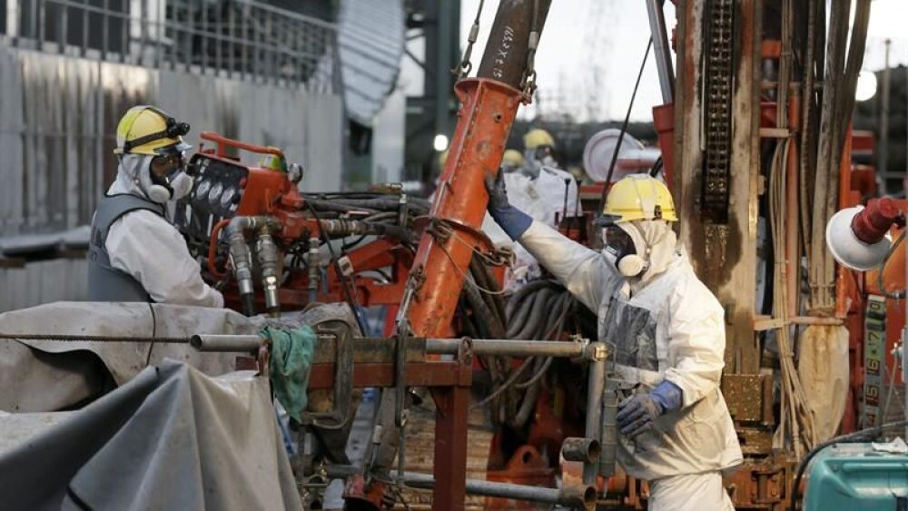 Varios trabajadores preparan tuberías heladas para construir un muro de hielo para congelar el agua radiactiva en la planta nuclear Tokyo Electric Power (TEPCO), en Okuma, Fukushima, al nordeste de Tokio, Japón.  El muro se construirá insertando una línea